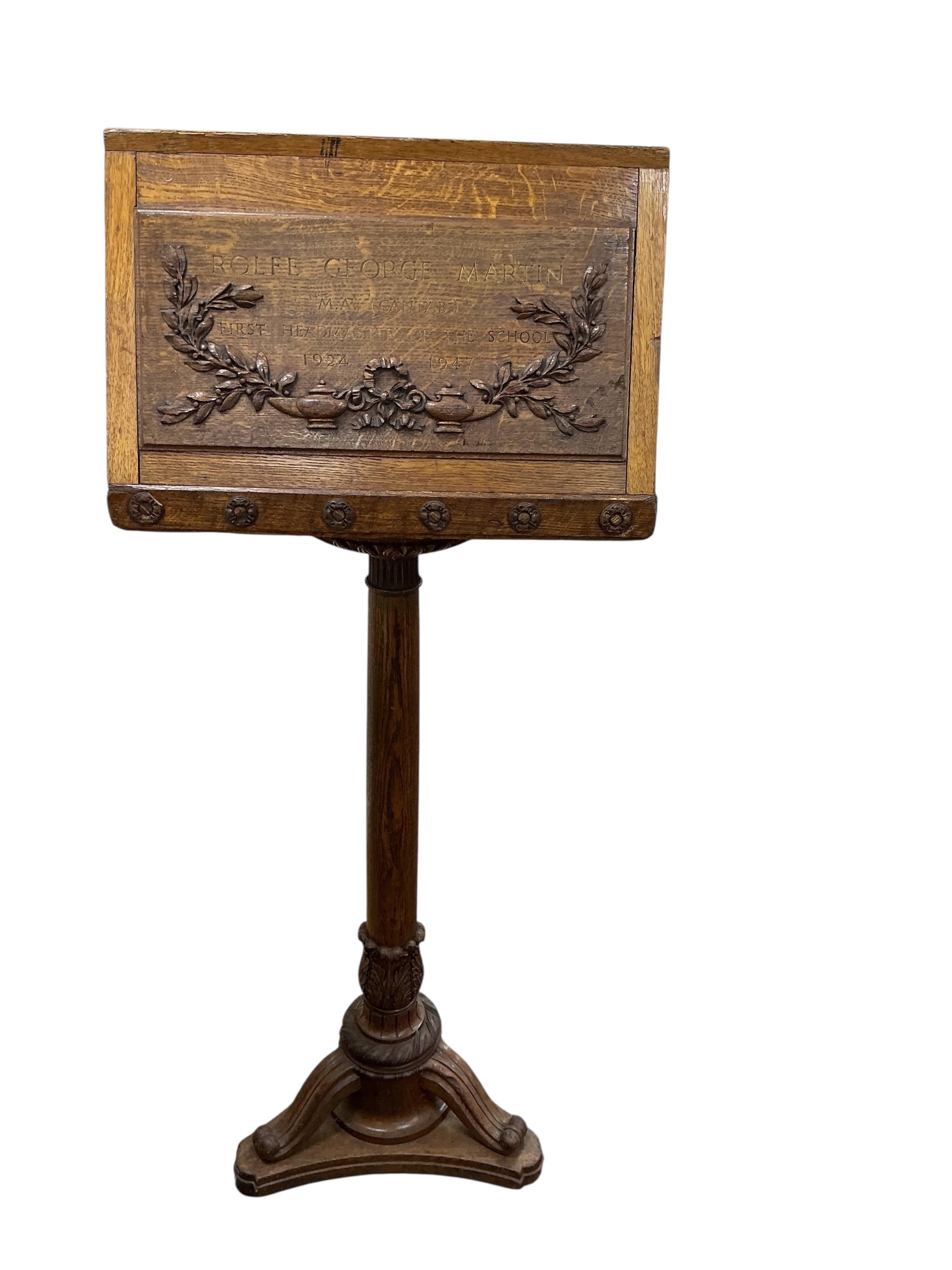 A mid 20th century oak lectern carved with ribbon fold floral swag and the legend “Rolfe George Martin, M.A (Cantab), First Headmaster of The School, 1924 - 1947. Height 142cm.